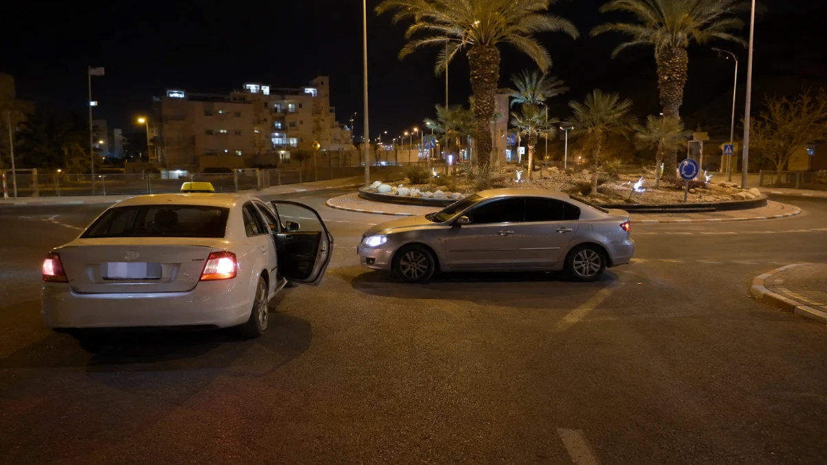 מונית עצורה בלילה במעגל תנועה עירוני באילת ורכב נוסף חוסם את דרכה, ללא אנשים נראים