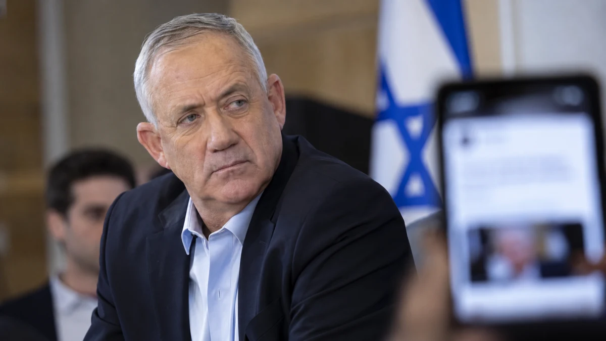 בנימין גנץ לצד טלפון חכם המציג פרסום מטושטש ברשת חברתית