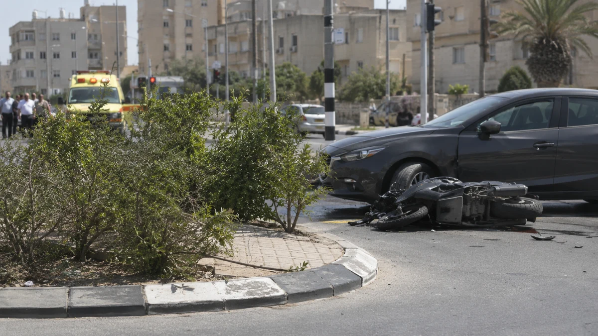 אופנוע פגוע ורכב בצומת עירוני עם אי תנועה וצמחייה, בהמחשה לתאונה בכפר קאסם