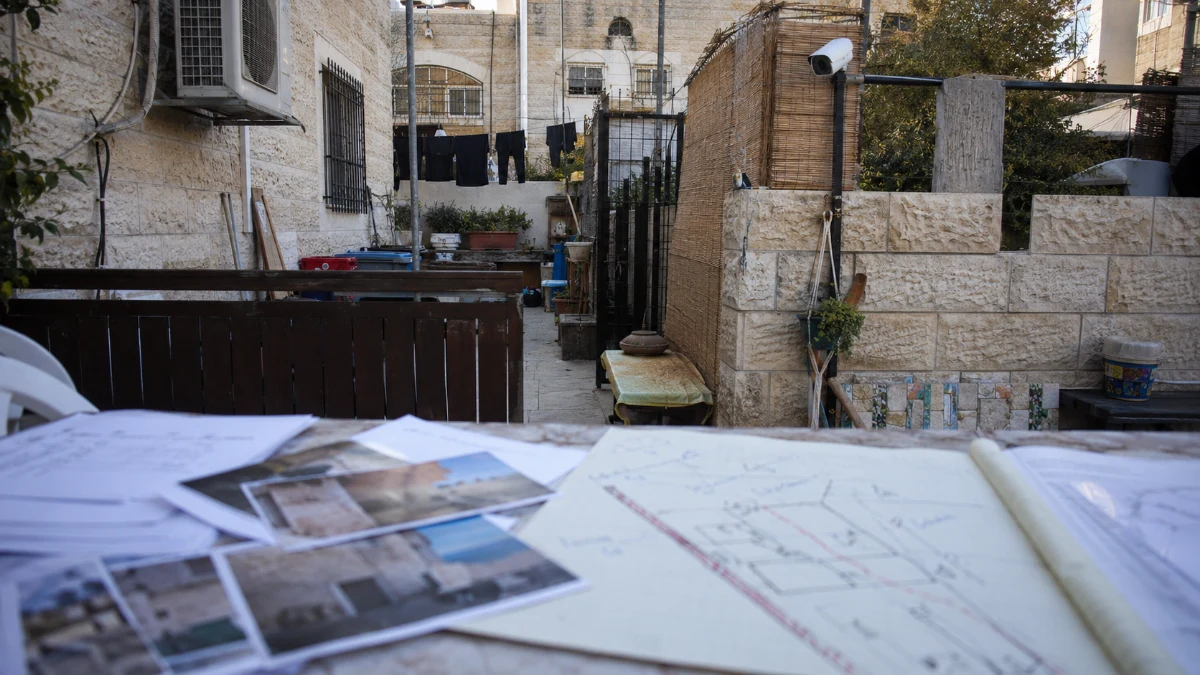 חצר משותפת בין שתי דירות עם גדר, מצלמה וחפצים מפוזרים ללא אנשים מזוהים
