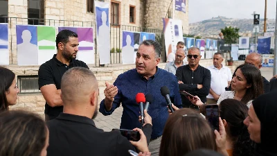 מערכת בחירות מקומית בעוספיה, עם שלטי מועמדים לא מזוהים ודיון ציבורי על התנהלות המועצה