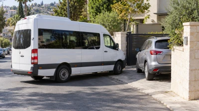 רכב מסחרי גדול סמוך לחניה פרטית חסומה ברחוב עירוני, בזירת האירוע שתואר בתביעה לתאונת עבודה